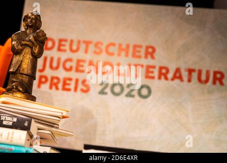 Berlin, Deutschland. Oktober 2020. Eine Preisfigur des Deutschen Jugendliteraturpreises 2020 steht auf einem Bücherhaufen vor dem Logo. Während der 72. Frankfurter Buchmesse wurde der Deutsche Jugendliteraturpreis 2020 per Livestream verliehen. Quelle: Christophe Gateau/dpa/Alamy Live News Stockfoto