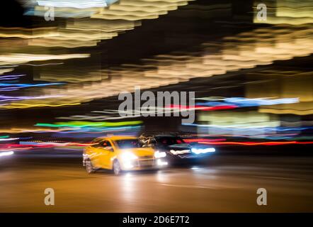 Gelbes Taxi auf einer Straße in der Stadt bei Nacht, absichtliche Bewegung verschwimmen Stockfoto