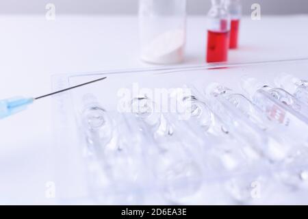 Spritze und eine Reihe von Fläschchen Medizin auf einem weißen Tisch. Horizontale Zusammensetzung. Vordergrund. Stockfoto