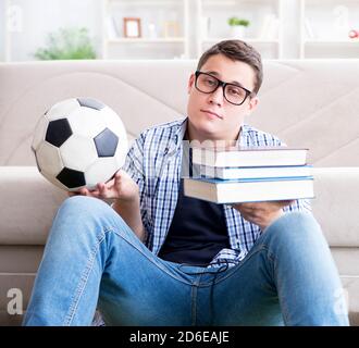 Der junge Student versucht zu studieren und spielen Fußball Stockfoto