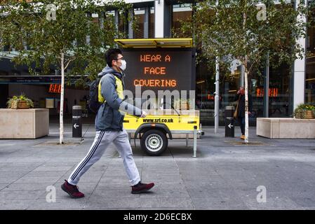 London, Großbritannien. Oktober 2020. Ein Mann mit Gesichtsmaske geht an einem digitalen Schild vorbei, das die Öffentlichkeit daran erinnert, außerhalb der London Bridge Station ''˜eine Gesichtsbedeckung zu tragen'. Quelle: Dave Rushen/SOPA Images/ZUMA Wire/Alamy Live News Stockfoto