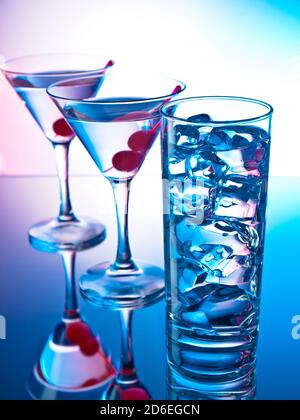 Zwei Gläser martini mit roten Kirschen und ein Glas Von klarem Cocktail Stockfoto