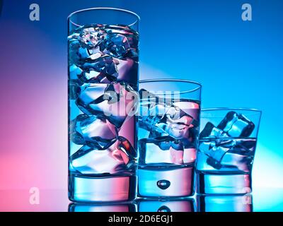 Drei Cocktails in verschiedenen Gläsern auf rosa und blauem Hintergrund Stockfoto