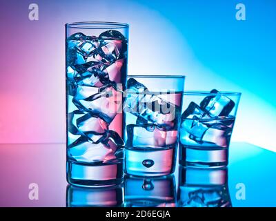 Drei Cocktails in verschiedenen Gläsern auf rosa und blauem Hintergrund Stockfoto