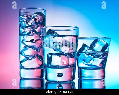 Drei Cocktails in verschiedenen Gläsern auf rosa und blauem Hintergrund Stockfoto
