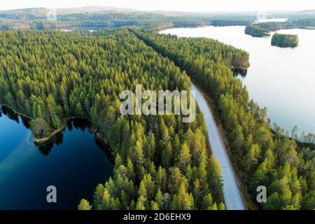 Luftaufnahme einer Straße zwischen Wald und Seen im Sommer in Nordfinnland. Stockfoto