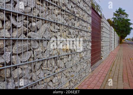 Gabionen. Ein Fragment eines Zauns aus Gabionen. Trennung der Straße von Wohngebieten. Stockfoto