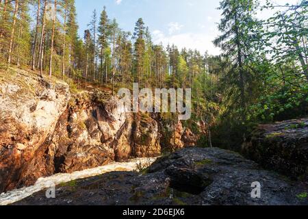 Oulanka National Park. Kiutaköngäs Stromschnellen Wasserfall mit rotem Kalkstein Felswand während eines sommerlichen Sonnenaufgangs in der finnischen Natur, Nordeuropa. Stockfoto