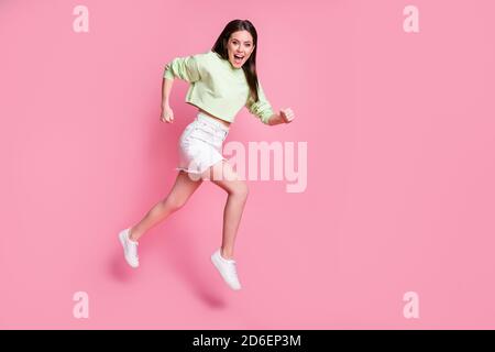 Full size-Profil Seite Foto von überrascht energetische Mädchen zu hören Unglaubliche Rabatte News jump laufen schnell tragen grün weiß stilvoll Modische Pullover-Schuhe Stockfoto