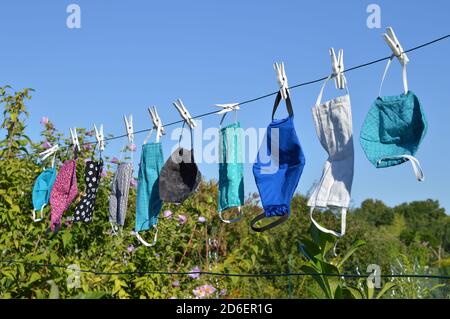 Viele verschiedene bunte selbst gemachte Corona Gesichtsmasken Aus Stoff hängen an einer Wäscheleine zum Trocknen Stockfoto