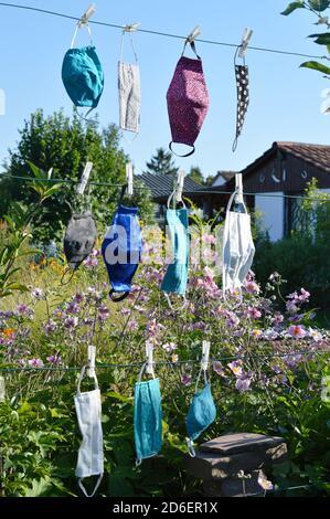 Viele verschiedene bunte selbst gemachte Corona Gesichtsmasken Aus Stoff hängen an einer Wäscheleine zum Trocknen Stockfoto
