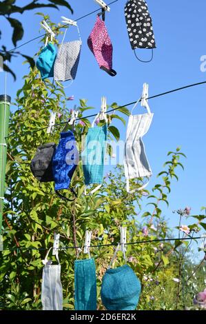Viele verschiedene bunte selbst gemachte Corona Gesichtsmasken Aus Stoff hängen an einer Wäscheleine zum Trocknen Stockfoto