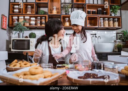 Asiatische Mutter und Tochter machen und schmücken Donuts. Machen Sie Donuts zusammen in der Küche Stockfoto