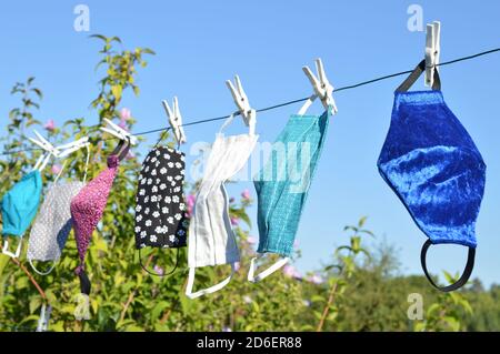 Viele verschiedene bunte selbst gemachte Corona Gesichtsmasken Aus Stoff hängen an einer Wäscheleine zum Trocknen Stockfoto