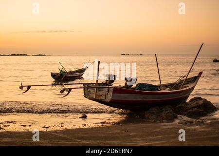 Zwei traditionelle Holzboote an der Küste bei einem hellen, schönen Sonnenuntergang in der Nähe von Ngwesaung Strand, Irrawaddy, West-Myanmar Stockfoto