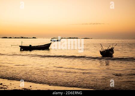 Drei traditionelle Holzboote am Ufer während eines hellen schönen Sonnenuntergangs in der Nähe von Ngwesaung Strand, Irrawaddy, West-Myanmar Stockfoto