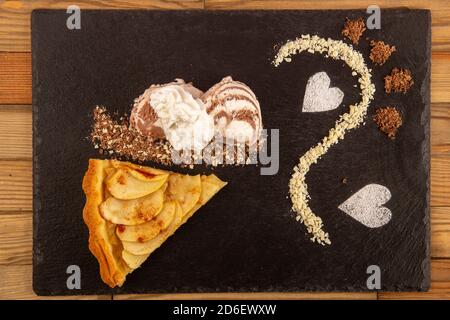 Tarte mit Äpfeln und Eis mit Schokoladenspäne auf einer Steinbasis. Herzförmige Streuseln. Stockfoto