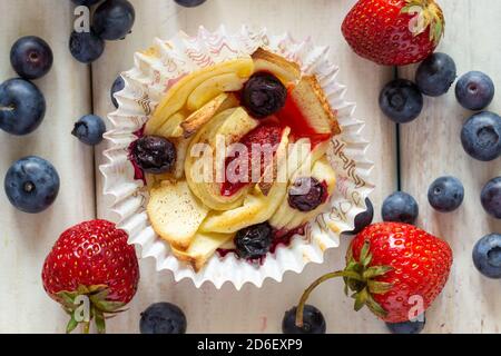 Tartlet mit Erdbeeren, Äpfeln, Heidelbeeren und Zimt auf Holzgrund. Frisches und gebackenes Obst. Stockfoto