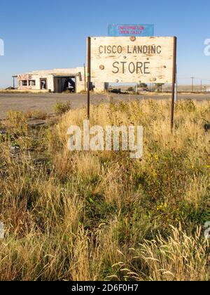 Eine alte Namenstafel für den Laden mit einer Ruine im Hintergrund in der Geisterstadt Cisco Landing, einer alten Bahnhofsstadt in Utah, USA Stockfoto