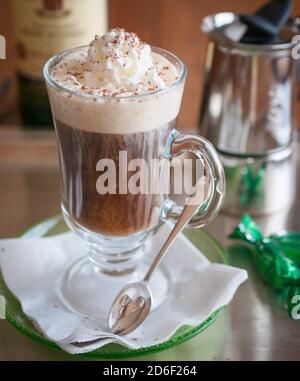 Nahaufnahme irisches Kaffeegetränk in transparentem Glas mit Schlagsahne und verschwommenem Hintergrund. Irischer Whiskey. Studioaufnahme. In Innenräumen. Stockfoto