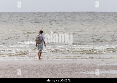 Entspannung bei jedem Wetter: Eine Frau wagt durch das Wasser und genießt das Meer und die Nordsee. Stockfoto