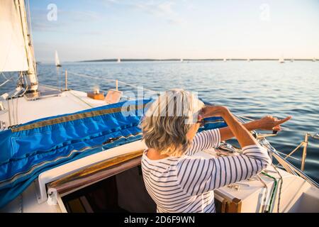 Frau mittleren Alters zeigt während Sommer segeln goldene Stunde Stockfoto