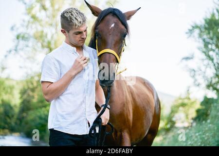 Porträt eines blonden jungen Mannes mit einem Pferd Stockfoto