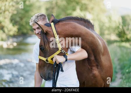 Porträt eines glücklichen blonden jungen Mannes mit einem Pferd Stockfoto
