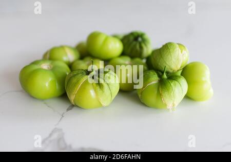 Eine Gruppe frisch gepflückter grüner Tomatillo-Früchte auf einer weißen Theke. Stockfoto