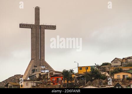 Coquimbo, Chile - 7. Dezember 2008: Nahaufnahme der hohen Millennium Cross Trinity, umgeben von Häusern in verschiedenen Farben unter einer blutigen Wolkenlandschaft. Stockfoto