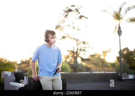 Teenager-Mann auf dem Dach hört Musik auf seinem Wireless Kopfhörer Stockfoto