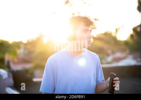 Teenager-Mann auf dem Dach hört Musik auf seinem Wireless Kopfhörer Stockfoto