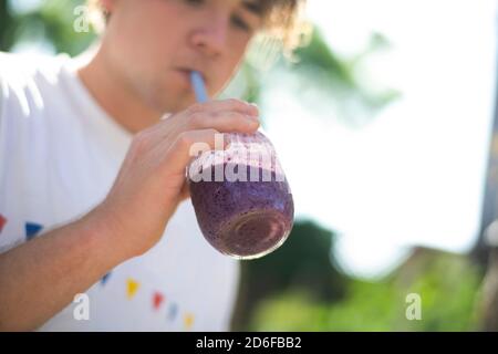 Blick von unten auf einen Teenager-Jungen, der eine Beere trinkt Smoothie aus dem Einmachglas Stockfoto