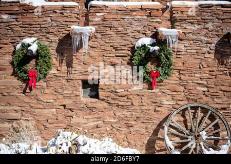 Winterkränze und Eiszapfen hängen an der Seite eines adobe-Haus Stockfoto