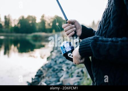 Junge Jungen Hände halten eine Angelrute beim Angeln an Sonnenuntergang Stockfoto