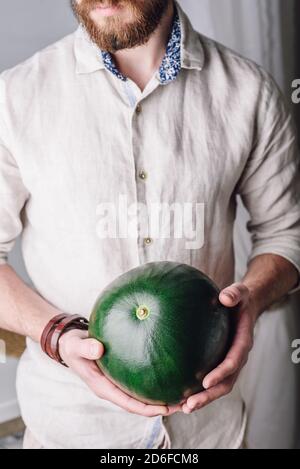 Bärtiger Mann mit ganzer Wassermelone in den Händen Stockfoto