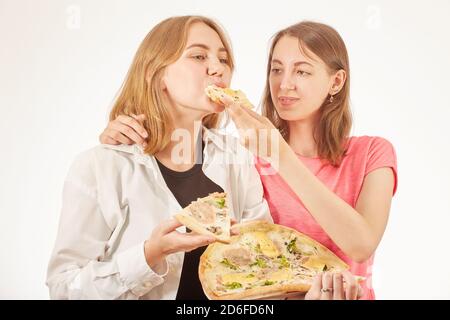 Zwei Mädchen essen Pizza auf weißem Hintergrund und lachen Stockfoto