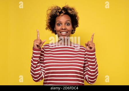 Stilvolle junge Frau zeigt und schaut vor weißem Hintergrund Stockfoto