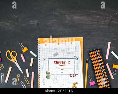 Zurück zur Schule, Bildungskonzept. Mehrfarbiges Notizbuch, Kreide, Schere, Globus, Büroklammern, Radiergummi, Stift und Bleistift isoliert auf Tafel Backgroun Stockfoto