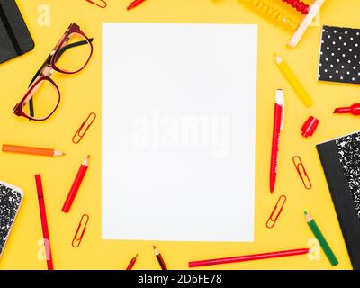 Zurück zur Schule, Bildungskonzept. Weißes Blatt mit roten Schulwerkzeugen, Brillen, Büroklammern, Taschenrechner Stifte um isoliert auf gelbem Farbstudio Stockfoto