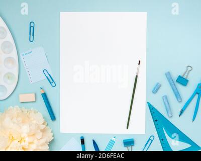 Zurück zur Schule, Bildungskonzept. Schreibwaren, Schule Werkzeuge in der Nähe eines weißen Blatt Papier und Maler Pinsel auf sie isoliert auf blaue Farbe Studio backgrou Stockfoto