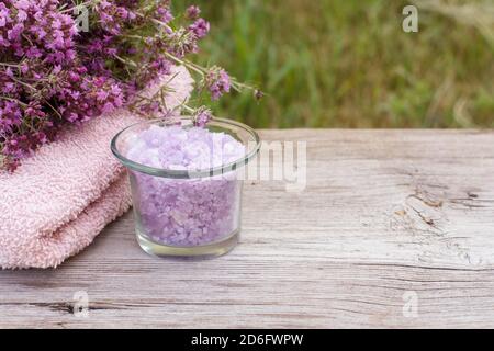 Terry Handtuch für Badezimmerverfahren mit Thymianblumen und Glasschale mit Meersalz auf Holztafeln. Spa-Produkte und Zubehör. Stockfoto