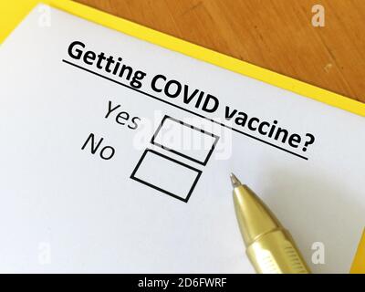Eine Person beantwortet die Frage. Die Person denkt, ob sie Coronavirus-Impfstoff bekommt. Er wählt ja oder nein Stockfoto