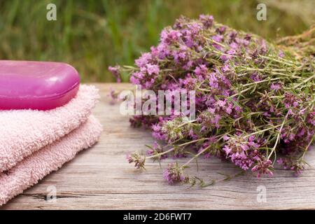 Terry Handtuch für Badezimmerverfahren mit Thymianblumen und Seife auf Holzbrettern. Spa-Produkte und Zubehör. Stockfoto