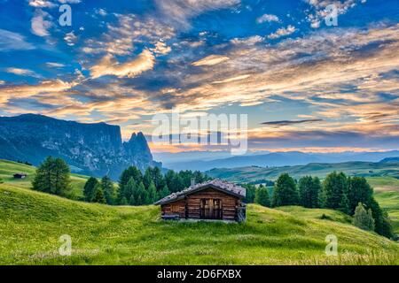 Hügeligen landwirtschaftlichen Landschaft mit grünen Weiden und ein Holzhaus auf der Seiser Alm, Seiser Alm, Schlern, Schlern, die Berge in der Ferne, an Stockfoto