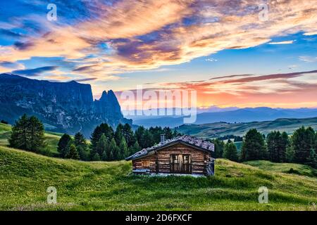 Hügeligen landwirtschaftlichen Landschaft mit grünen Weiden und ein Holzhaus auf der Seiser Alm, Seiser Alm, Schlern, Schlern, die Berge in der Ferne, an Stockfoto