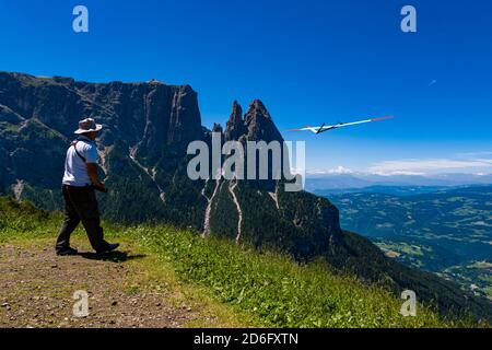 Ein Mann startet ein Modellflugzeug auf der Seiser Alm, der Seiser Alm, dem Schlern, Schlern, in der Ferne. Stockfoto