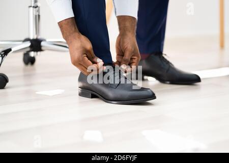 Afrikanisch Amerikanischer Mann, Der Schuhe Im Büro-Stockwerk Wechselt Stockfoto