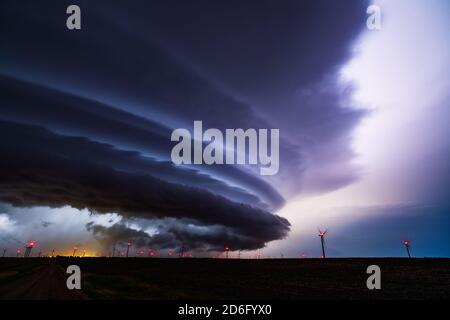 Supercell-Sturmwolken, die vom Blitz am Nachthimmel über einem Windpark in Spearville, Kansas, erleuchtet werden Stockfoto
