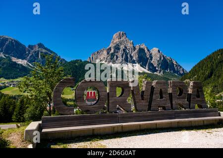 Berg Mt. Sassongher, Sass Songher, über der Stadt und grünen Weiden, der Name Corvara in Holz geschnitten. Stockfoto